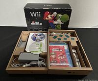 Full view of the Wii console box with organized components inside including power adapter, controllers, game discs and manuals