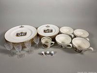 Photo showing entire lot laid out including plates, mugs, shot glasses, and thimbles to document quantity and condition.