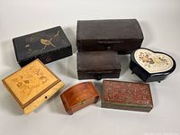 Seven vintage trinket and storage boxes arranged together showing a variety of materials and designs.