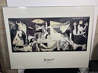 Full view of framed Picasso Guernica print with broken glass visible in lower left corner.