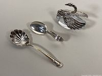 Photo showing two sterling silver spoons and crystal swan salt cellar