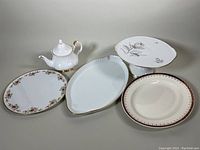 Assorted porcelain and bone china lot with platter, plates, and teapot all on flat surface