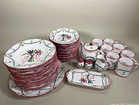 Full set of hand painted earthenware dinnerware including plates, mugs, teapot, creamer, and salt and pepper shakers arranged on table.