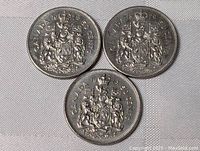 Three Canadian half dollar coins from the 1970s shown together on a fabric background, showing both front details and condition.