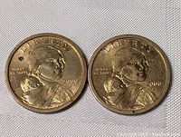 Obverse sides of two 2000 USA Sacagawea $1 coins, showing Sacagawea with infant and date 2000