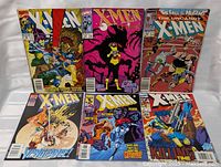 Photo of 6 Marvel Comics X-Men comic books laid out showing full covers.