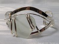 Close-up view of silver plated cuff bracelet with large frosted pale green stone from one angle.