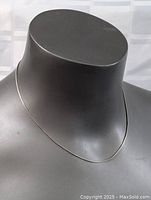 Sterling silver chain necklace displayed on a black mannequin bust, showing the thin and sleek design of the chain.