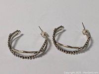 Pair of vintage sterling silver hoop earrings with an abstract design featuring beaded edges and wavy horizontal bar, displayed flat on a white surface