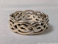 Close-up photo of the sterling silver Celtic twist ring on a light fabric background showing the detailed braided knot pattern.