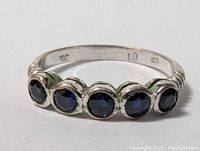 Close up photo of the ring front showing five round dark blue sapphire stones set in sterling silver with visible 925 stamp inside the band.