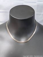 Front view of thick sterling silver necklace displayed on black mannequin bust, showing flat woven chain and reflective surface.