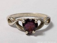 Close-up front view of sterling silver ring with purple tourmaline round stone and open loop design band.