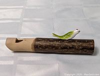 Photo showing the vintage carved bird whistle from a side angle, highlighting the wooden base and bird figure.