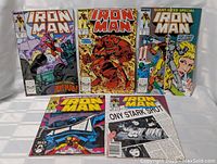 Photo showing 6 vintage Iron Man Marvel comic books with colorful covers posing upright.