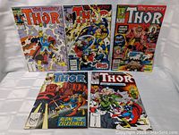 Full front view of all five vintage Marvel 'The Mighty Thor' comic books arranged in two rows on white cloth background.