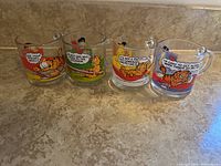 Photo showing front views of all four Garfield and McDonald's glass coffee mugs with colorful cartoon graphics and speech bubbles.