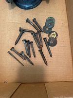 Top-down photo showing assorted square head nails with attached heads and several metal washers, all placed on cardboard background.