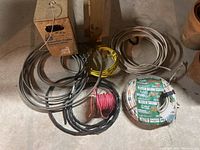 Wide view of all electric cables and wires including coiled colored wires and a cardboard box.