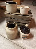 Four farmhouse crocks displayed on and around a rustic wooden crate on concrete floor, showing general set appearance.