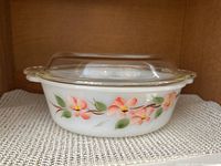 Front side view of the Federal Oven Ware covered oval casserole showing floral pattern on white glass base with clear glass lid on top.