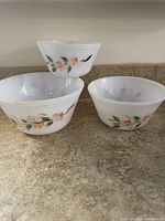 Three Federal Oven Ware nested mixing bowls arranged with the smallest bowl placed on top of the second largest bowl. Floral pattern on white milk glass visible.