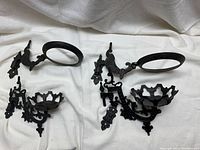 Four swing arm wall sconces laid out on a white cloth, showing ornate metalwork and circular holders.