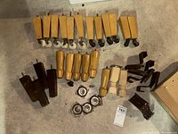 Photo showing an assortment of wooden furniture legs including tapered, turned, painted, and block legs with caster wheels plus angled wooden supports and metal brackets on concrete floor.