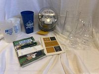 Full view of memorabilia laid out on white cloth showing electric meter, cups, glasses, booklet and handbook