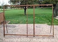 Wooden rectangular stretching frame standing outdoors on a patio with angled legs visible.