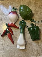 Overview of 6 ceramic vegetable-themed measuring cups shaped like various vegetables including turnip, green leaf, green pepper, leek, and chili peppers