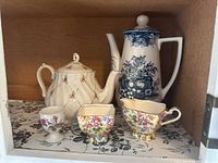 Photo shows Sadler England teapot with pink rose motif to the left, Hara Blue coffee pot with blue floral pattern to the right, and floral egg cup in front center. Also visible Royal Winton floral sugar bowl and creamer.
