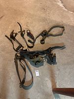 Photo of all vintage lineman equipment laid out on concrete floor, showing leather belts, gaffs, straps, and tool pouch.