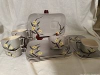 Overview of the 6 luncheon sets with plates and matching square cups showing floral design and cup holders.