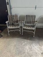 Front view showing two metal frame folding chairs with wooden slats on seat and back and rounded wood armrests.