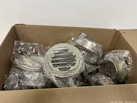 Photo of multiple stainless steel chimney cowl air vent caps inside a cardboard box, wrapped in plastic.