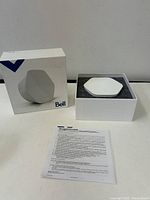 Bell Capsule Wi-Fi 6E router and its box. Paper with printed text included.
