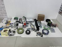 Wide view of all hardware and accesssories on table showing multiple tape rolls, fasteners, bolts, pipe, and tools.