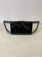 Front of the rectangular car stereo media receiver with touchscreen display and side plastic trim.