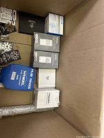 Top view of large cardboard box showing various packaged items including wheel hub rings, WSXA auto relays, and other components in their boxes and bags.