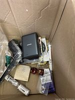 Box with Anker charger, toy car, black tools, and small packaged items