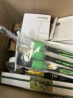 View into the box showing Energify branded garden digging tools, Benchmark branded box, and other items packed inside