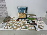 Image showing assorted seed packets spread out, a green tarp in packaging, 3-pack wasp traps box, and some cans.