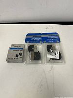 Three packages of Shimano disc brake pads on white background, two H03C models in blister packs and one H03A boxed set.