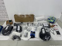 Photo showing a variety of cycling and outdoor accessories packed on a table, including gloves, arm sleeves box, small bike parts, water bottle, and reflective strap.