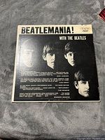 Front cover of the vinyl album titled 'Beatlemania! With The Beatles' featuring the portraits of the Beatles members and album title.