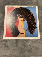 Front cover of Billy Squier Emotions in Motion LP showing stylized colorful portrait on the sleeve.