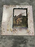 Front cover of the Led Zeppelin IV vinyl album, showing the old man carrying sticks artwork with wear and some discoloration on the cover edges.
