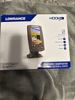 Box of Lowrance HOOK 4 fishfinder chartplotter showing brand and model with key features.