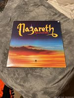 Front cover of Nazareth Greatest Hits vinyl LP album showing colorful sunset background and large band name text.